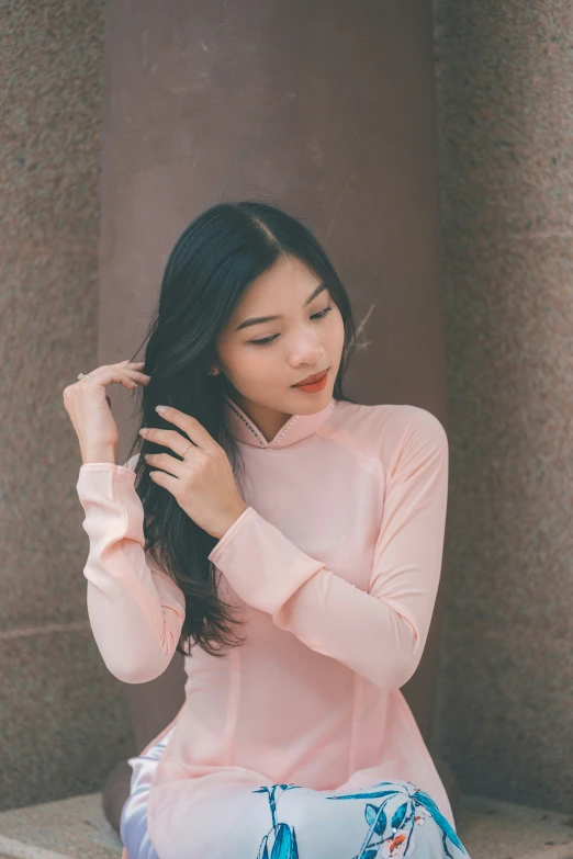 a beautiful young woman in a pink top sitting down