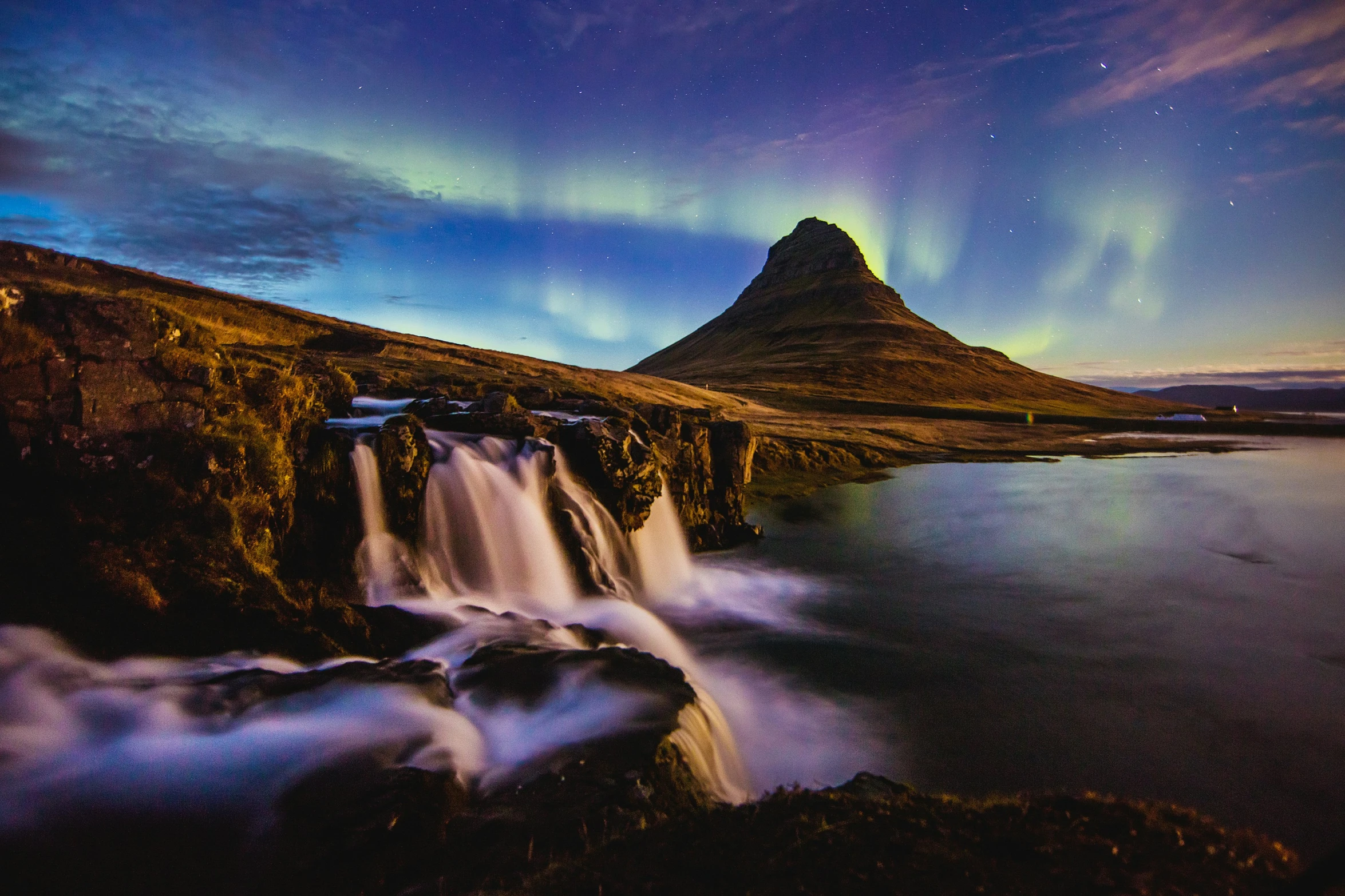 a rocky mountain with a waterfall and a night sky