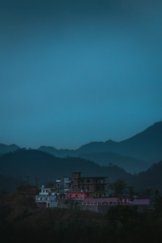 a dark green sky with some houses under a hill