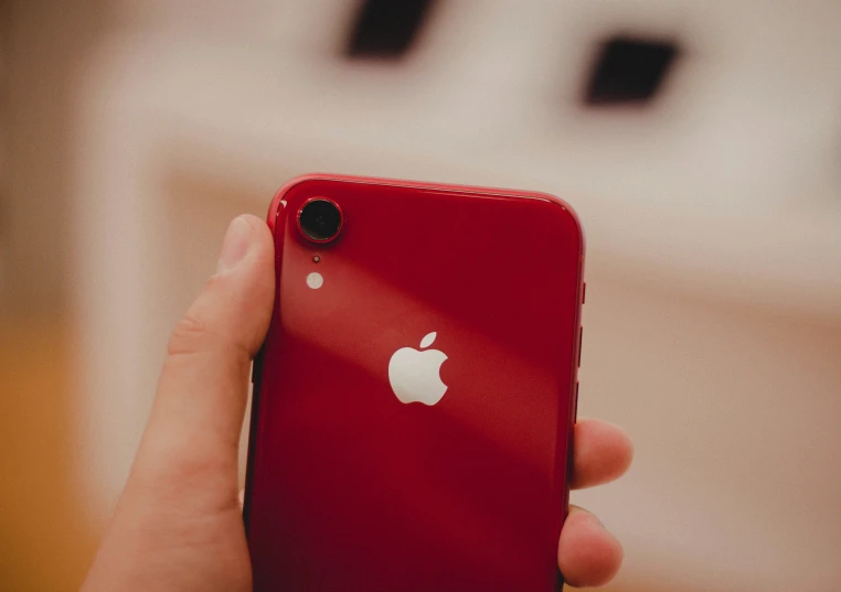 a hand holding a red iphone with the apple logo on it