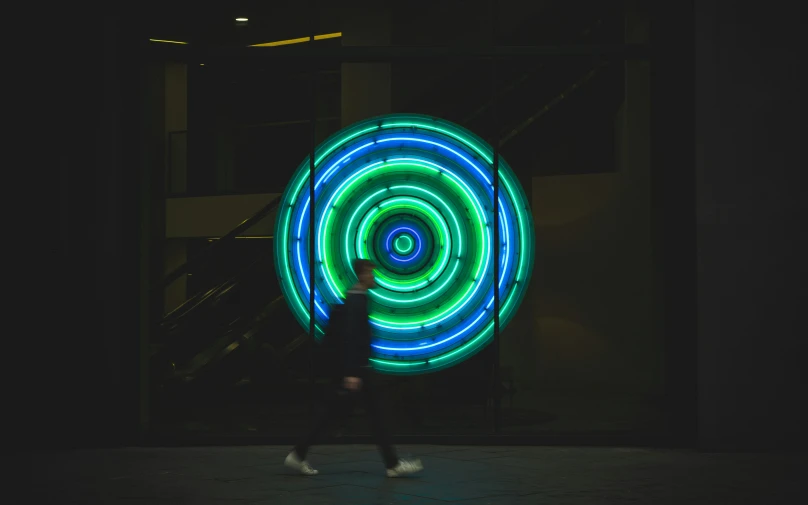 a person running near a giant neon light ring