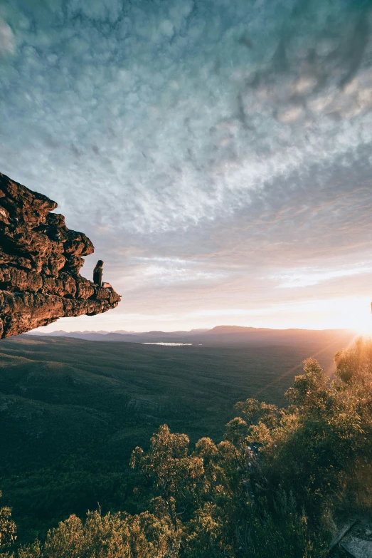 a person with a backpack on looking at a sunset