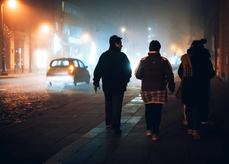 people walking down the sidewalk on a rainy night