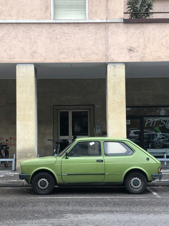 a green car is parked in front of a building