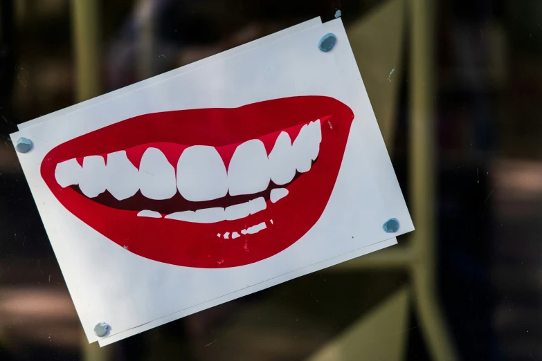 a white sign with red mouths and white teeth is hanging on a door