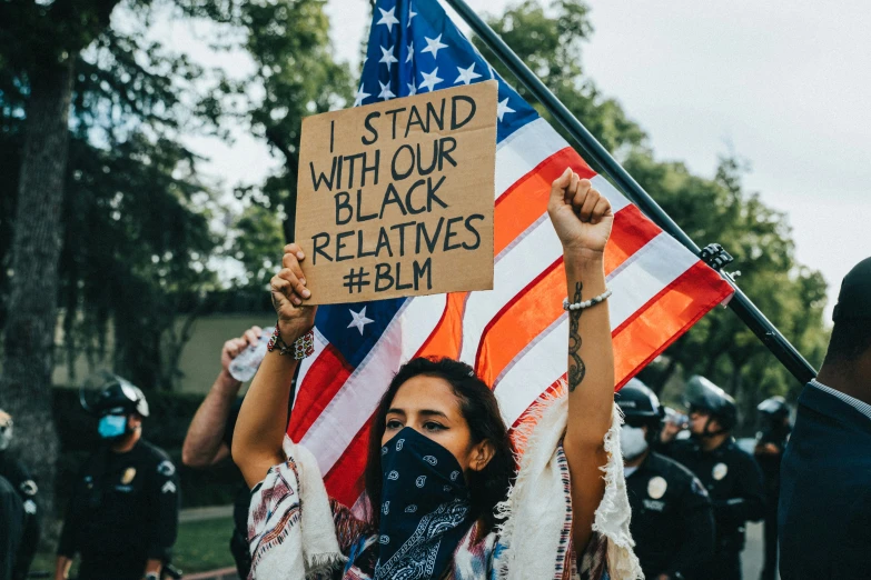 the protestors are holding signs in front of an american flag