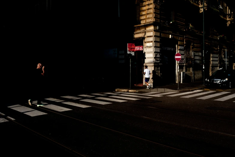 a man walks across a city street at night