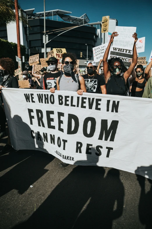 people standing on the street holding protest signs