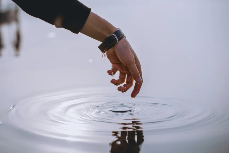 a hand reaches out from the water towards another person