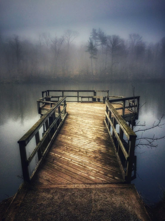 a dock with an old wooden pathway extending into a foggy lake