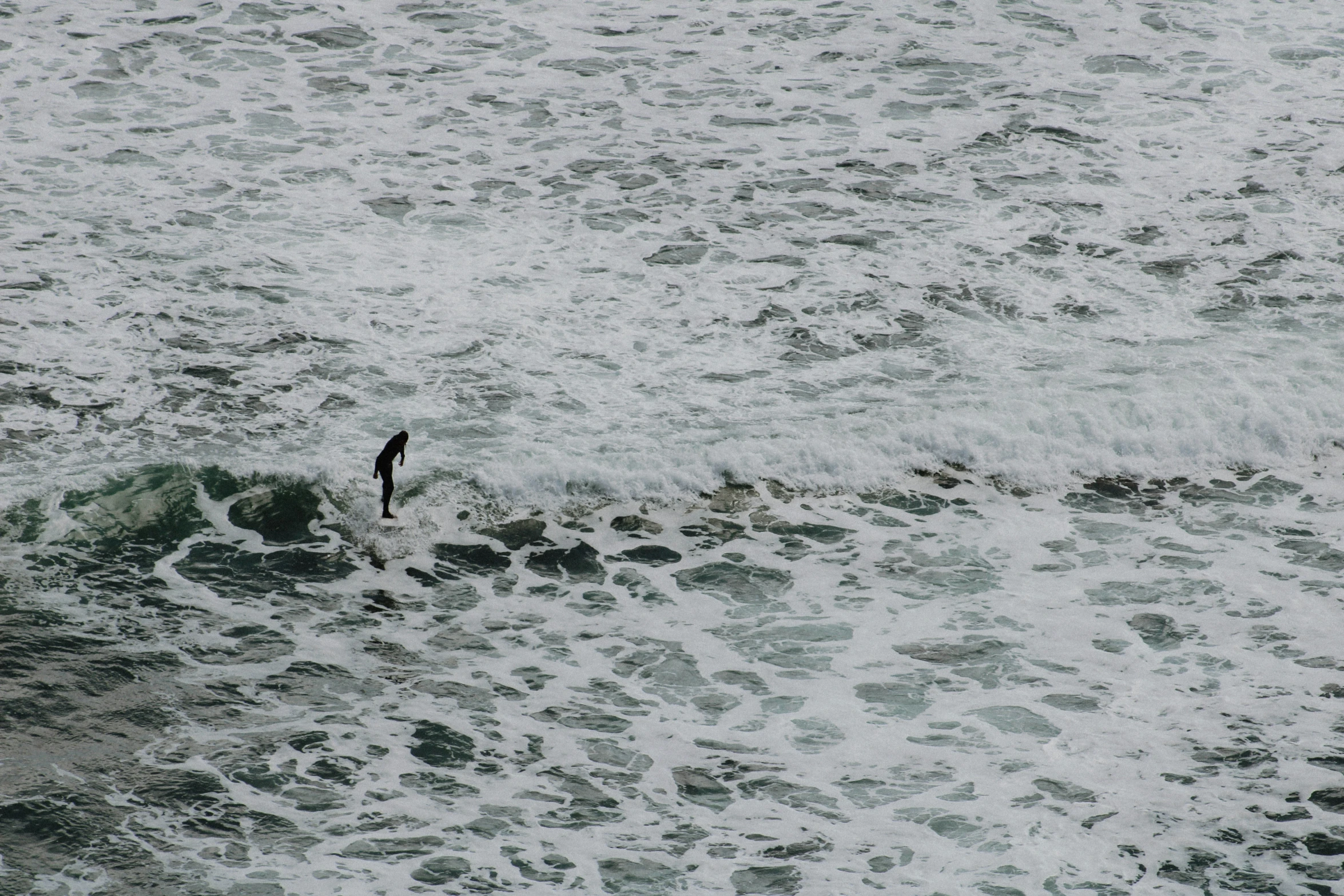 an individual is in the water near many waves