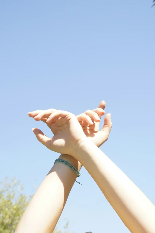 hands reaching up to catch a kite in the air