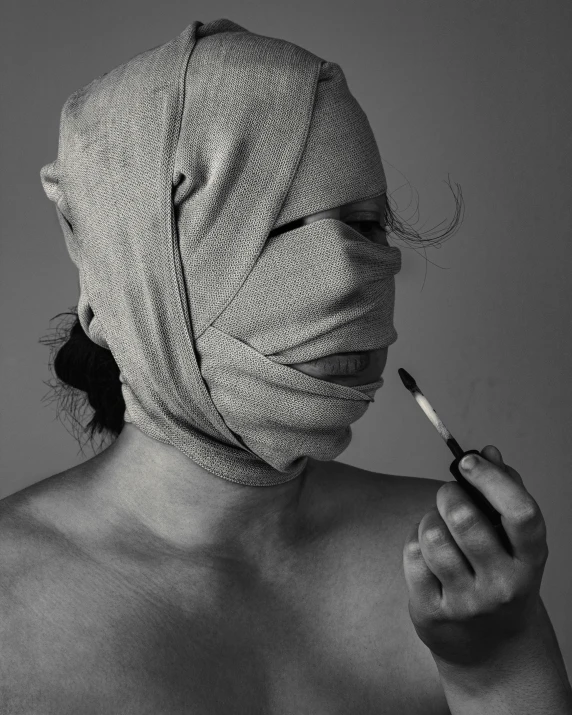 woman with makeup and face covered by a mask holding a cigarette