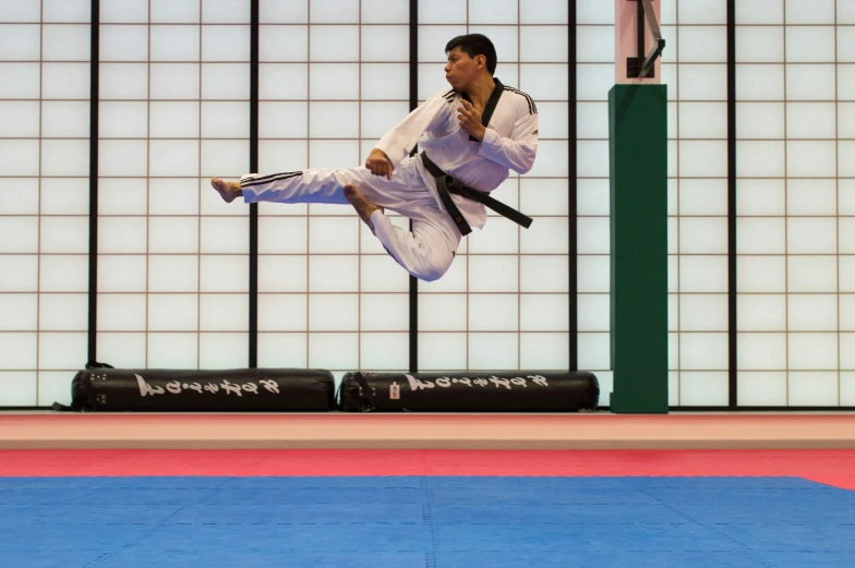 an adult male jumping in the air on a black belt