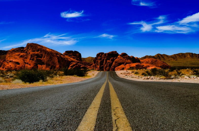 a long paved road in the desert with rocks