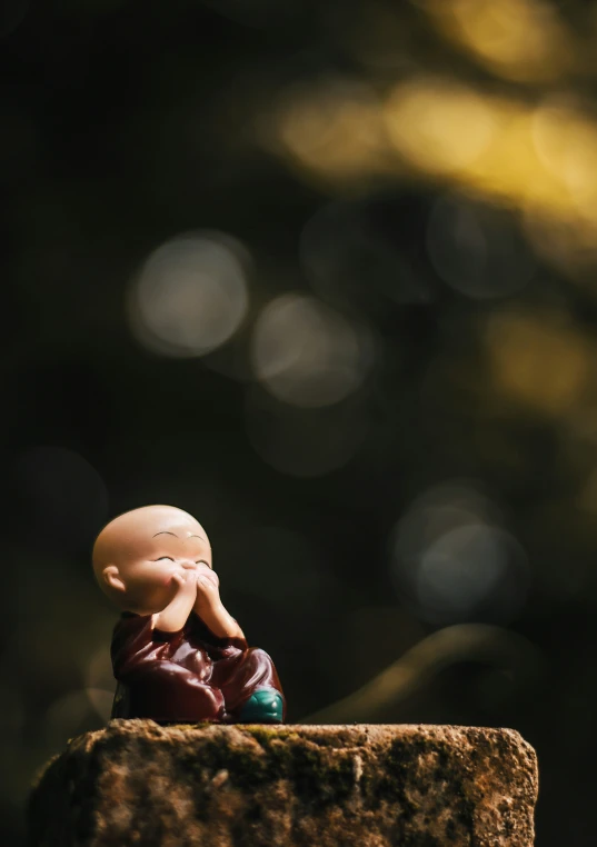 small figurine sitting on top of a stone block