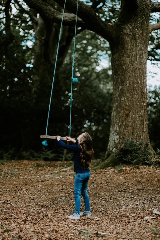 a little girl swinging a swing set by the trees