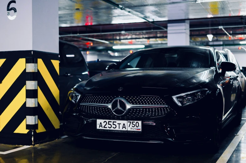 the rear of two black mercedes benz cars in a parking garage