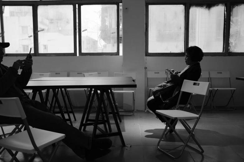 two people sitting in a room with small tables and stools