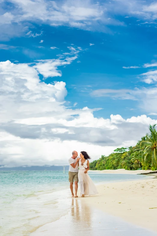 the bride and groom walk through the water on the beach