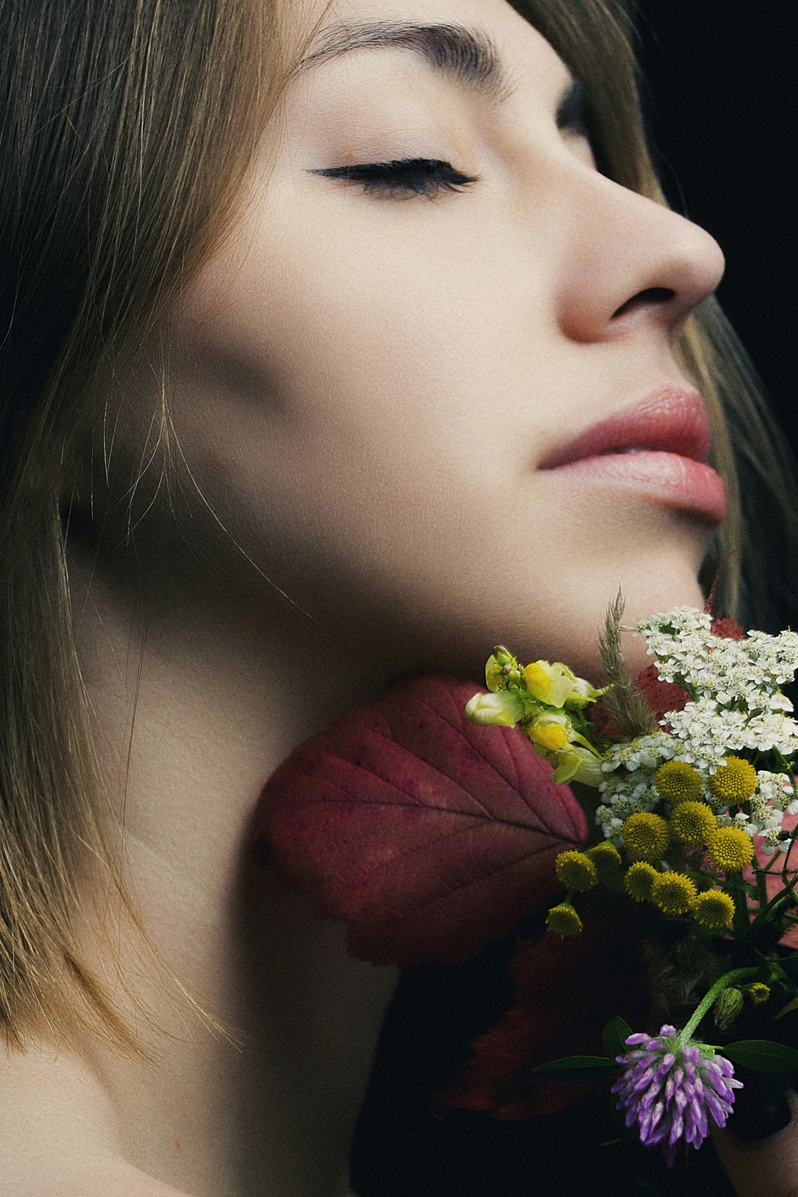 the face of a woman smelling some flowers