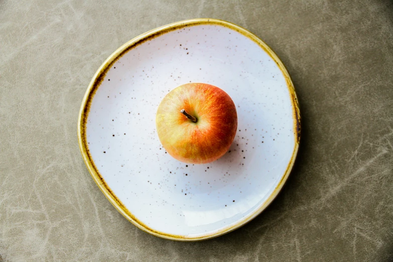 a yellow rimmed plate with an apple in it