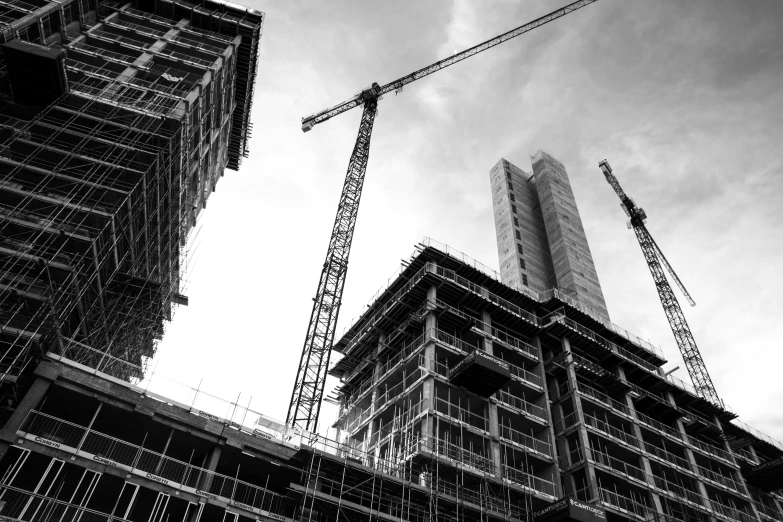 cranes are perched over some buildings under a cloudy sky