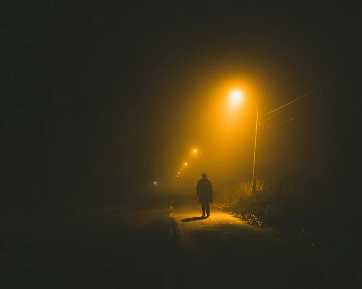 a man standing on a street at night under a light