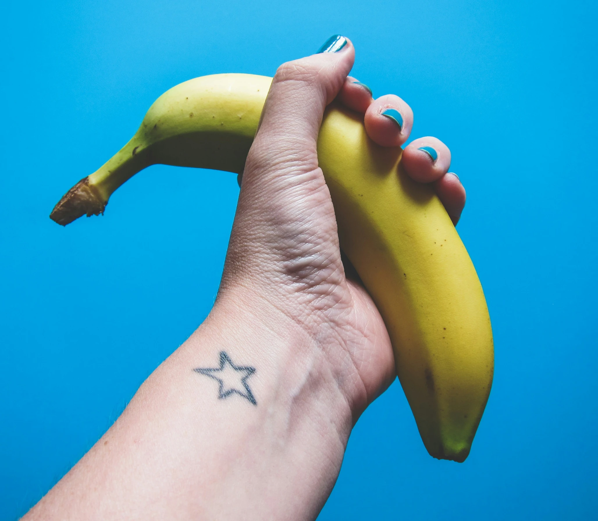 a woman's arm is covered in small stars while holding a banana