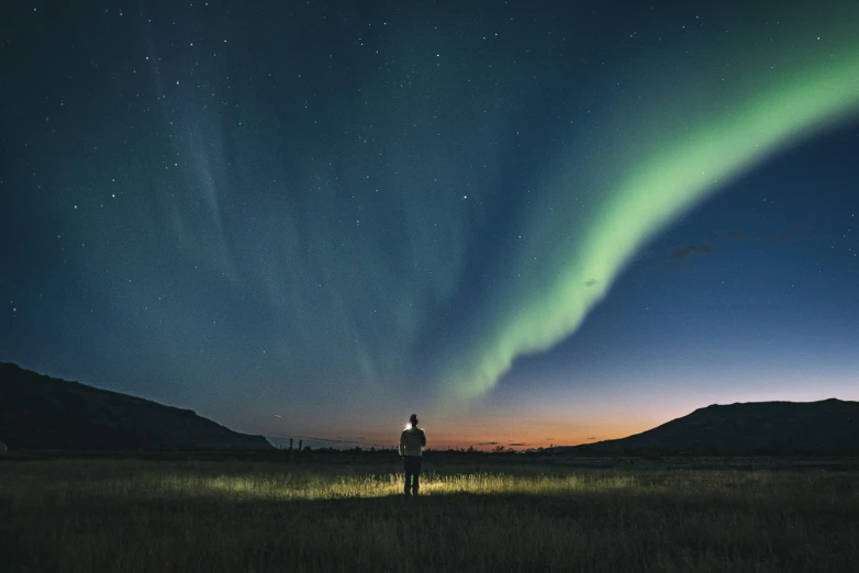 an aurora sign with bright green lights in the sky above a grass field