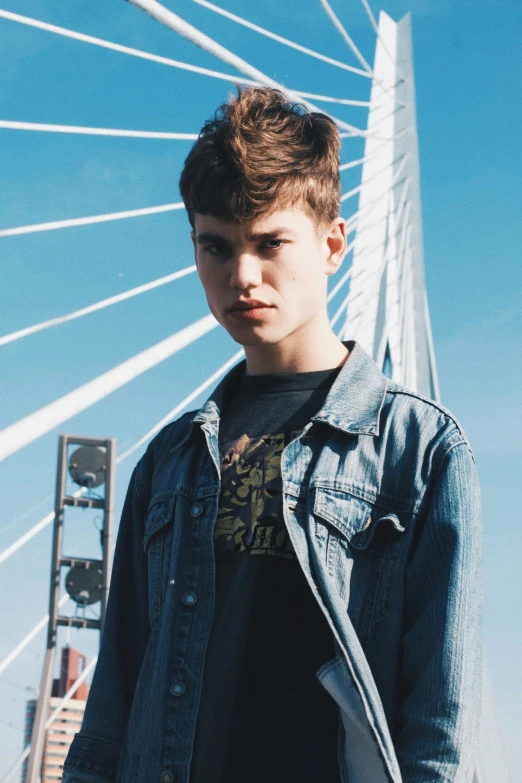 a boy standing by a bridge wearing a jacket