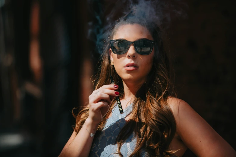 a beautiful young lady wearing sunglasses smoking a cigarette