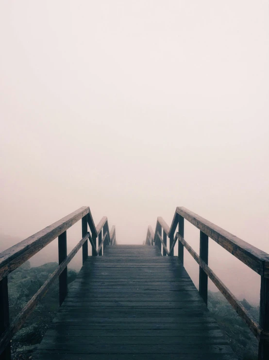 there is a long boardwalk on a foggy day