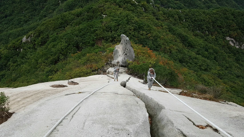 a man on a suspension bridge between two large mountains