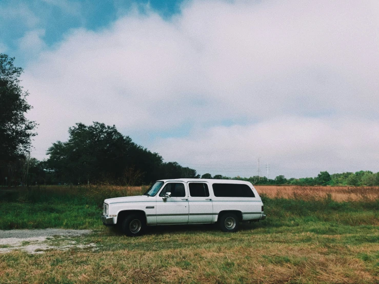 a white truck parked in a field on a cloudy day