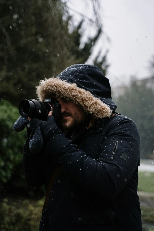 a man wearing a hat holding a camera up to his face