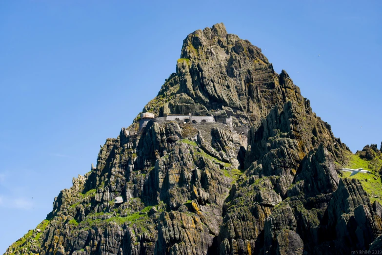 a large rock mountain towering into the blue sky