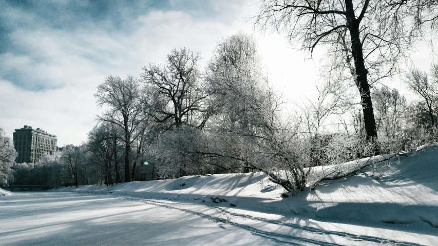 a snow covered park path near tall buildings