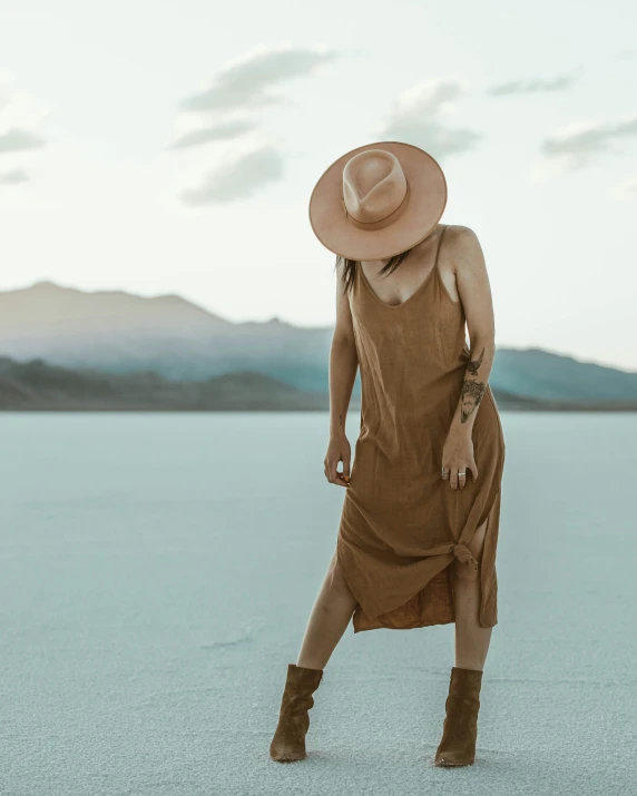 woman with large hat standing in an empty lake