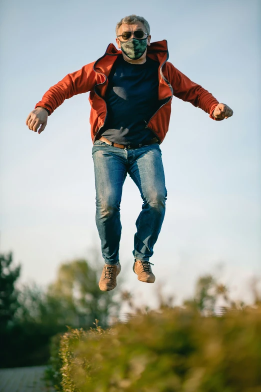 a man wearing an orange jacket jumping in the air on a skateboard