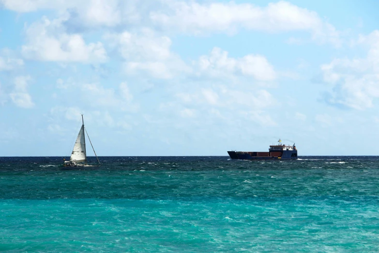 boat in bright blue water near sailboat off shore