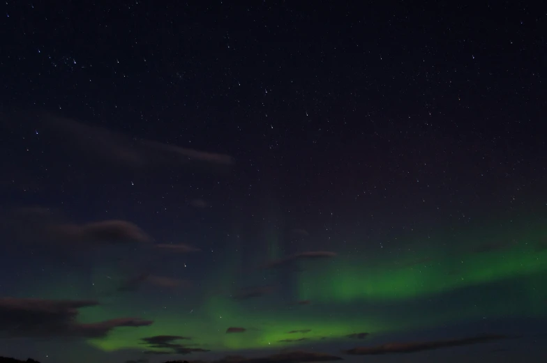 the sky is covered with green aurora lights