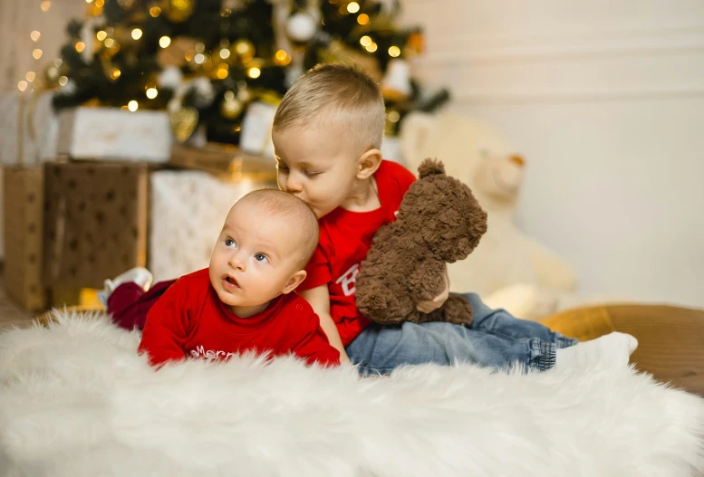 two children sitting on the floor playing with teddy bears