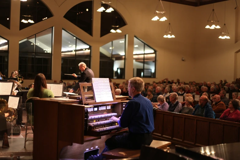 a concert in a large hall with a group of people sitting on the stage