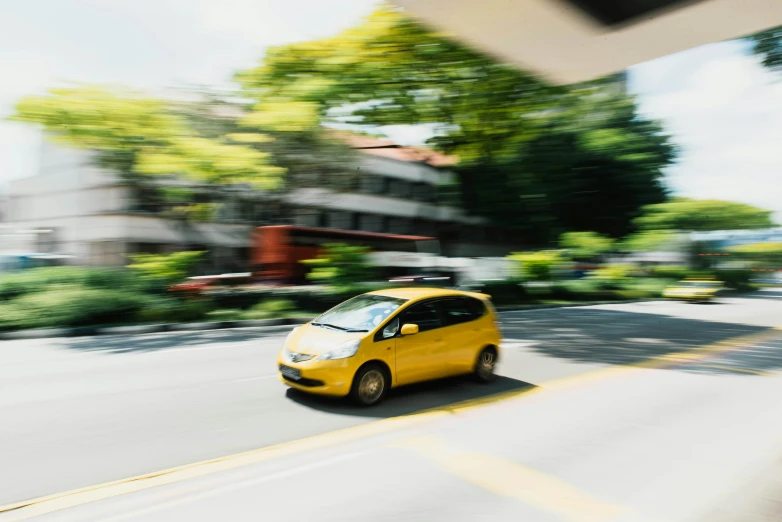 a small yellow car driving down a street