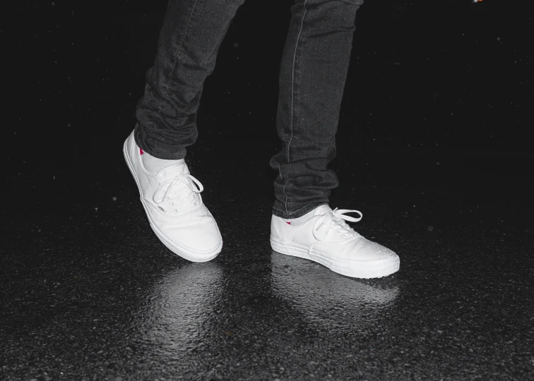 a man's foot in black and white shoes on a black surface