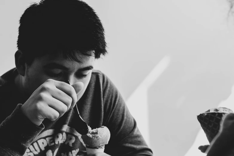 a black and white image of someone eating a pastry