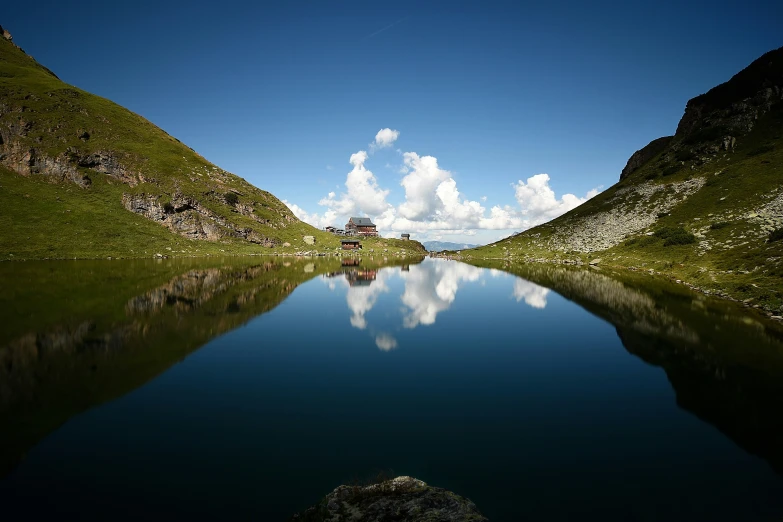 a small lake surrounded by mountains with reflection