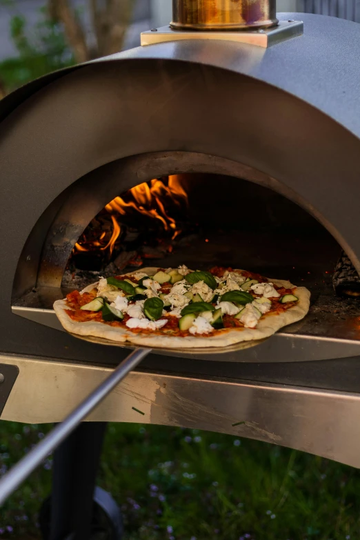 pizza coming out of a brick oven and on a grill