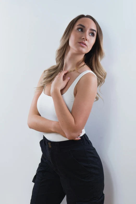 a woman is leaning against the wall and wearing black pants